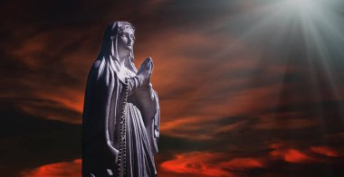 Bakire Meryem 'in antik heykeli kasvetli gökyüzünün dramatik manzarasına karşı dua ediyor.