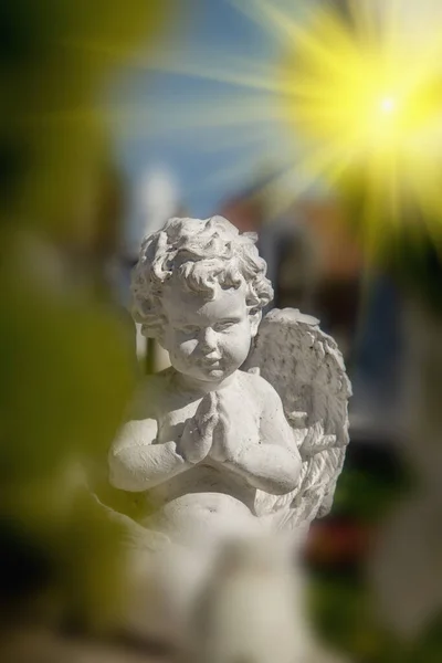 Ancient statue of little angel in sun light as symbol of the soul of a child.