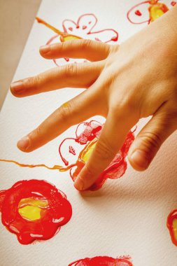 Parmak kadar güzel çiçekle resim yapan kız çocuğu. Dikey resim.