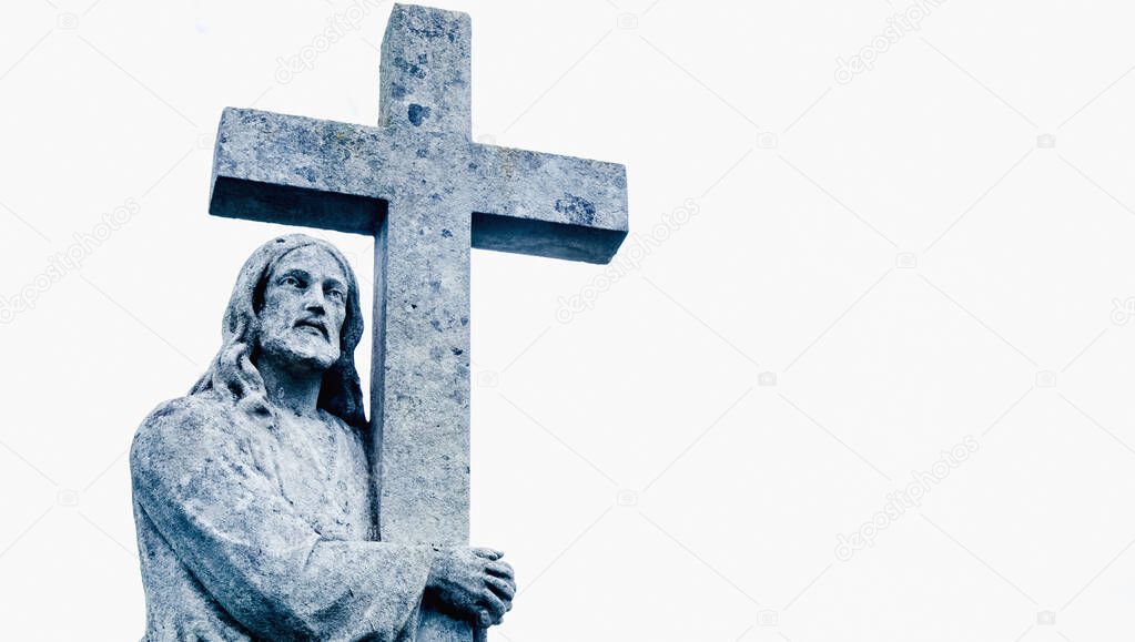 Ancient stone  statue of Jesus Christ with cross.  Free copy space for text or design. Horizontal image.