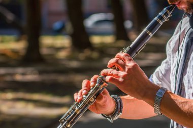 Yürüyen caddede klarnet çalan genç adamı kapat. Sokak müzisyeni. Müzik, sanat, yaratıcılık kavramı.