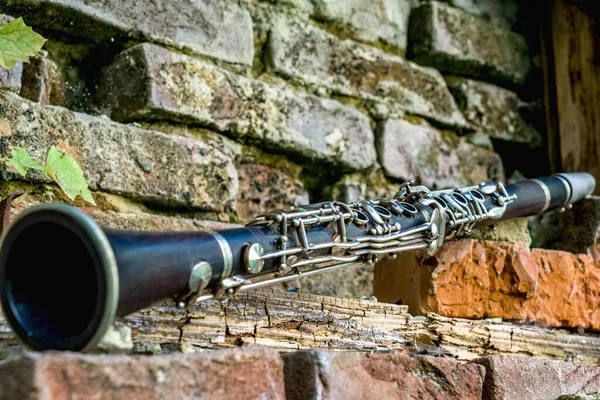 Old and dirty clarinet on a background of a beautiful old broken brick wall. Copy space for text or design.