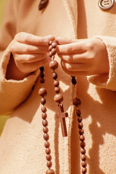 关闭年轻的女孩祈祷和持有一个木制念珠 垂直图像 — 图库照片