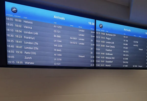 Arrivals display board at airport terminal showing international — Stock Photo, Image