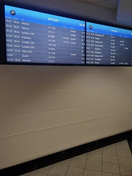 Arrivals display board at airport terminal showing international — Stock Photo, Image