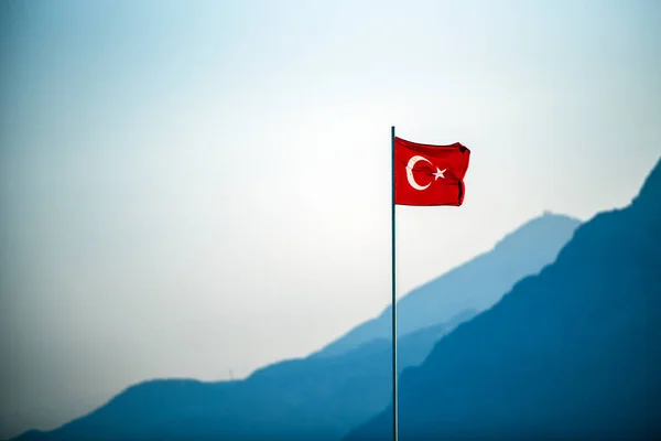 背景の山と風に揺れるトルコ国旗 — ストック写真