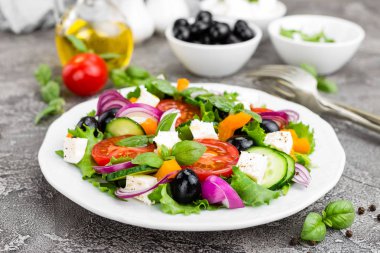 Yunan salatası. Domates, soğan, salatalık, fesleğen, biber, zeytin, marul ve beyaz peynir ile taze sebze salatası. Plaka üzerinde Yunan salatası
