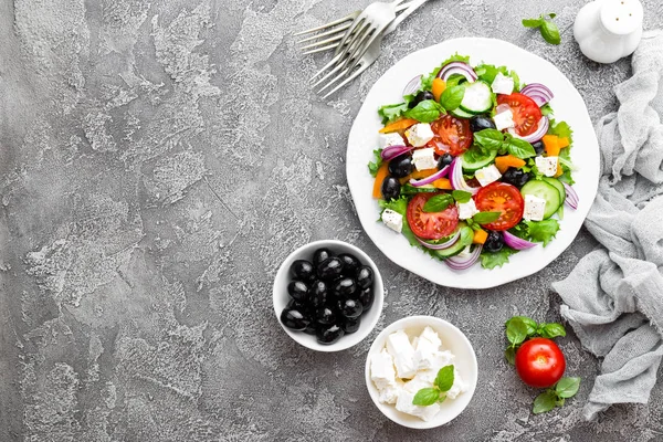 Greek salad. Fresh vegetable salad with tomato, onion, cucumbers, basil, pepper, olives, lettuce and feta cheese. Greek salad on plate