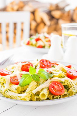 Makarna fesleğen pesto, domates ve peynirle plaka üzerinde