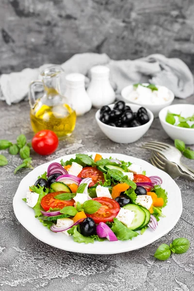 Greek salad. Fresh vegetable salad with tomato, onion, cucumbers, pepper, olives, lettuce and feta cheese. Greek salad on plate