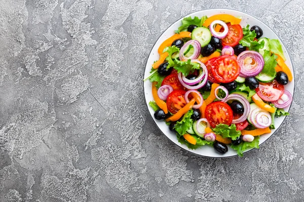 Greek salad. Fresh vegetable salad with tomato, onion, cucumbers, pepper, olives, lettuce and feta cheese. Greek salad on plate