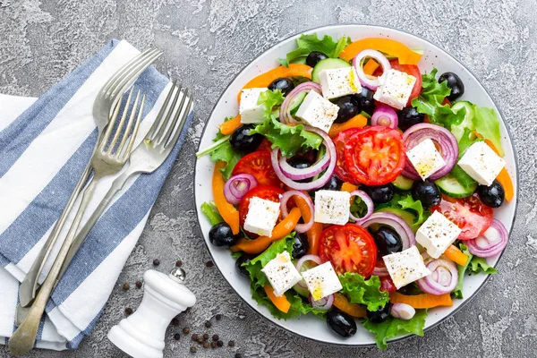 Greek salad. Fresh vegetable salad with tomato, onion, cucumbers, pepper, olives, lettuce and feta cheese. Greek salad on plate