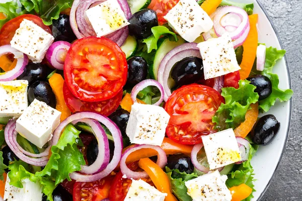 Greek salad. Fresh vegetable salad with tomato, onion, cucumbers, pepper, olives, lettuce and feta cheese. Greek salad on plate