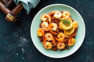 Karides ızgara kavrulmuş ve plaka üzerinde kahverengi pirinç haşlanmış. Izgara karides, karides pirinç. Deniz ürünleri. Asya mutfağı. Üstten Görünüm. Koyu arka plan