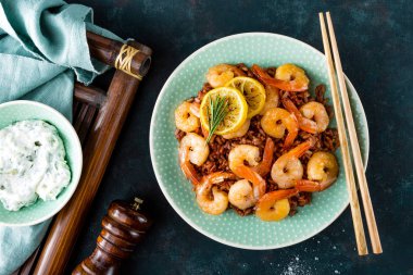 Karides ızgara kavrulmuş ve plaka üzerinde kahverengi pirinç haşlanmış. Izgara karides, karides pirinç. Deniz ürünleri. Asya mutfağı. Üstten Görünüm. Koyu arka plan