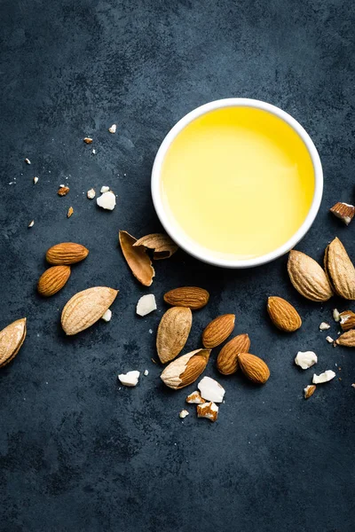 Almond oil in bowl and almond nuts. Almonds