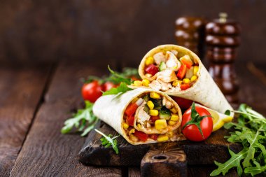 Burrito tamamladı tavuk eti ve sebze ahşap arka plan üzerinde