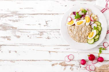 Haşlanmış yumurta ve taze turp, salatalık ve marul sebze salatası ile yulaf lapası. Sağlıklı diyet kahvaltı