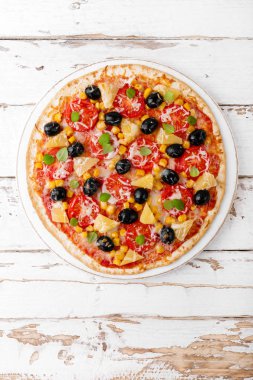Pizza domates, mozzarella peyniri, zeytin, Mısır ve fesleğen. Geleneksel İtalyan mutfağı. Üstten görünüm