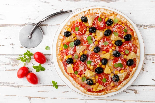 Pizza with tomatoes, mozzarella cheese, olives, corn and basil. Traditional italian cuisine. Top view