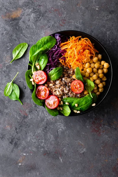 Healthy vegetarian dish with buckwheat and vegetable salad of chickpea, kale, carrot, fresh tomatoes, spinach leaves and pine nuts. Buddha bowl. Balanced food. Delicious detox diet.Top view