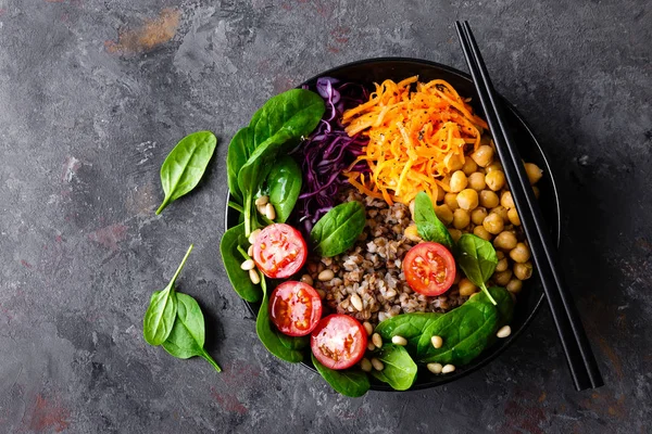 Healthy vegetarian dish with buckwheat and vegetable salad of chickpea, kale, carrot, fresh tomatoes, spinach leaves and pine nuts. Buddha bowl. Balanced food. Delicious detox diet.Top view