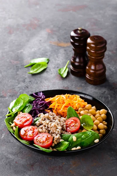 Healthy vegetarian dish with buckwheat and vegetable salad of chickpea, kale, carrot, fresh tomatoes, spinach leaves and pine nuts. Buddha bowl. Balanced food. Delicious detox diet