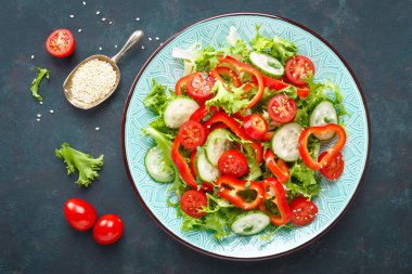 Sağlıklı vejetaryen sebze salatası, taze marul, salatalık, tatlı biber ve domates. Vegan gıda bitkisel kökenli. Düz yatıyordu. Üstten görünüm
