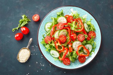 Sağlıklı vejetaryen sebze salatası, taze marul, salatalık, tatlı biber ve domates. Vegan gıda bitkisel kökenli. Düz yatıyordu. Üstten görünüm