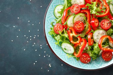 Sağlıklı vejetaryen sebze salatası, taze marul, salatalık, tatlı biber ve domates. Vegan gıda bitkisel kökenli. Düz yatıyordu. Üstten görünüm