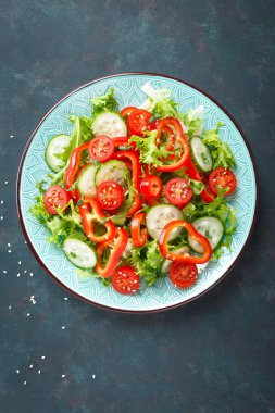 Sağlıklı vejetaryen sebze salatası, taze marul, salatalık, tatlı biber ve domates. Vegan gıda bitkisel kökenli. Düz yatıyordu. Üstten görünüm