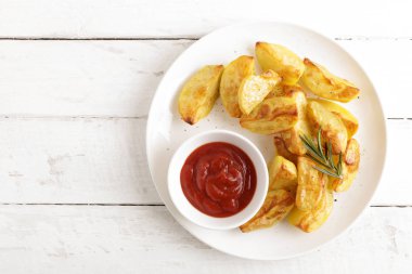 Fırında patates ve Domates ketçap beyaz tabak, ahşap arka plan, üstten görünüm