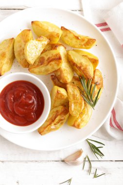 Fırında patates ve Domates ketçap beyaz tabak, ahşap arka plan, üstten görünüm