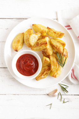 Fırında patates ve Domates ketçap beyaz tabak, ahşap arka plan, üstten görünüm