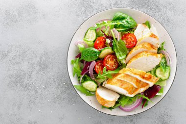 Izgara tavuk göğsü, fileto ve taze sebze salatası marul, roka, ıspanak, salatalık ve domates. Sağlıklı öğle yemeği menüsü. Diyet yemekleri. Üstten görünüm