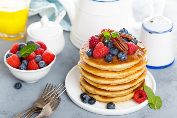 Stack of fluffy pancakes with fresh berries and pecan nuts