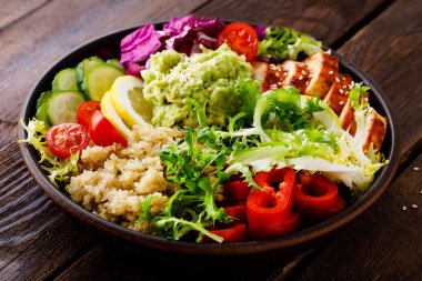 Buda kase yemek. Sağlıklı dengeli yemek quinoa, ızgara tavuk eti, marul salatası, biber, salatalık, domates ve avokado guacamole limon ile