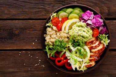 Buda kase yemek. Sağlıklı dengeli yemek quinoa, ızgara tavuk eti, marul salatası, biber, salatalık, domates ve avokado guacamole limon ile