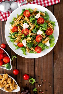İtalyan makarna salatası kepekli düdük, taze domates, peynir, marul ve brokoli ahşap rustik arka plan üzerinde. Akdeniz mutfağı. Öğle yemeği yemek. Sağlıklı bir diyet yemek. Üstten görünüm