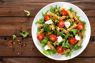 İtalyan makarna salatası kepekli düdük, taze domates, peynir, marul ve brokoli ahşap rustik arka plan üzerinde. Akdeniz mutfağı. Öğle yemeği yemek. Sağlıklı bir diyet yemek. Üstten görünüm