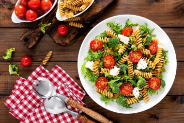 İtalyan makarna salatası kepekli düdük, taze domates, peynir, marul ve brokoli ahşap rustik arka plan üzerinde. Akdeniz mutfağı. Öğle yemeği yemek. Sağlıklı bir diyet yemek. Üstten görünüm