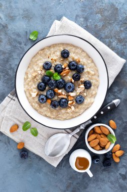 Taze çiğ yaban mersini, badem fındık ve bal kahvaltıda yulaf ezmesi. Sağlıklı vejetaryen yemek. Üstten görünüm