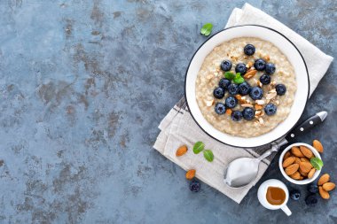 Taze çiğ yaban mersini, badem fındık ve bal kahvaltıda yulaf ezmesi. Sağlıklı vejetaryen yemek. Üstten görünüm