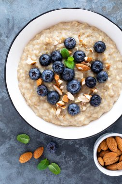 Taze çiğ yaban mersini, badem fındık ve bal kahvaltıda yulaf ezmesi. Sağlıklı vejetaryen yemek. Üstten görünüm
