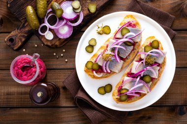 Koyu ahşap rustik arka plan üzerinde horseradish ile ringa balığı, soğan ve kırmızı pancar sos ile lezzetli ızgara sandviç. Danimarka mutfağı. Üstten görünüm