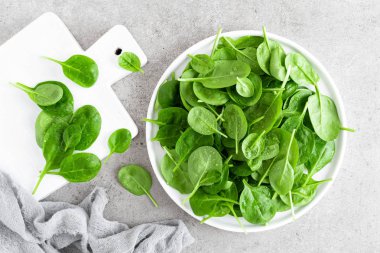 Taze ıspanak üzerinde beyaz tabak bırakır. Sağlıklı vegan gıda. Üstten görünüm