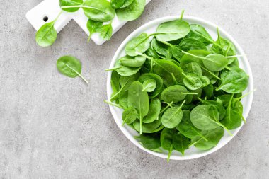 Taze ıspanak üzerinde beyaz tabak bırakır. Sağlıklı vegan gıda. Üstten görünüm