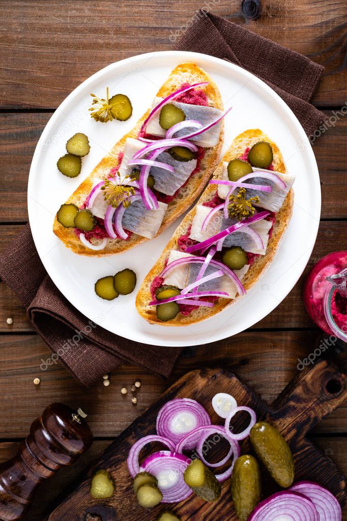 Delicious grilled sandwiches with herring, onion and beetroot sauce with horseradish on dark wooden rustic background. Danish cuisine. Top view