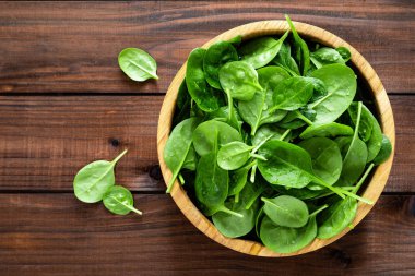 Taze ıspanak ahşap arka plan üzerinde bırakır. Sağlıklı vegan gıda. Top vie