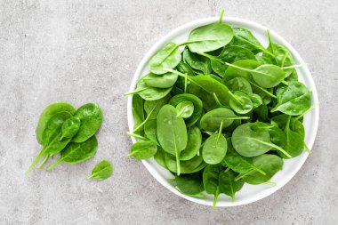 Taze ıspanak üzerinde beyaz tabak bırakır. Sağlıklı vegan gıda. Üstten görünüm